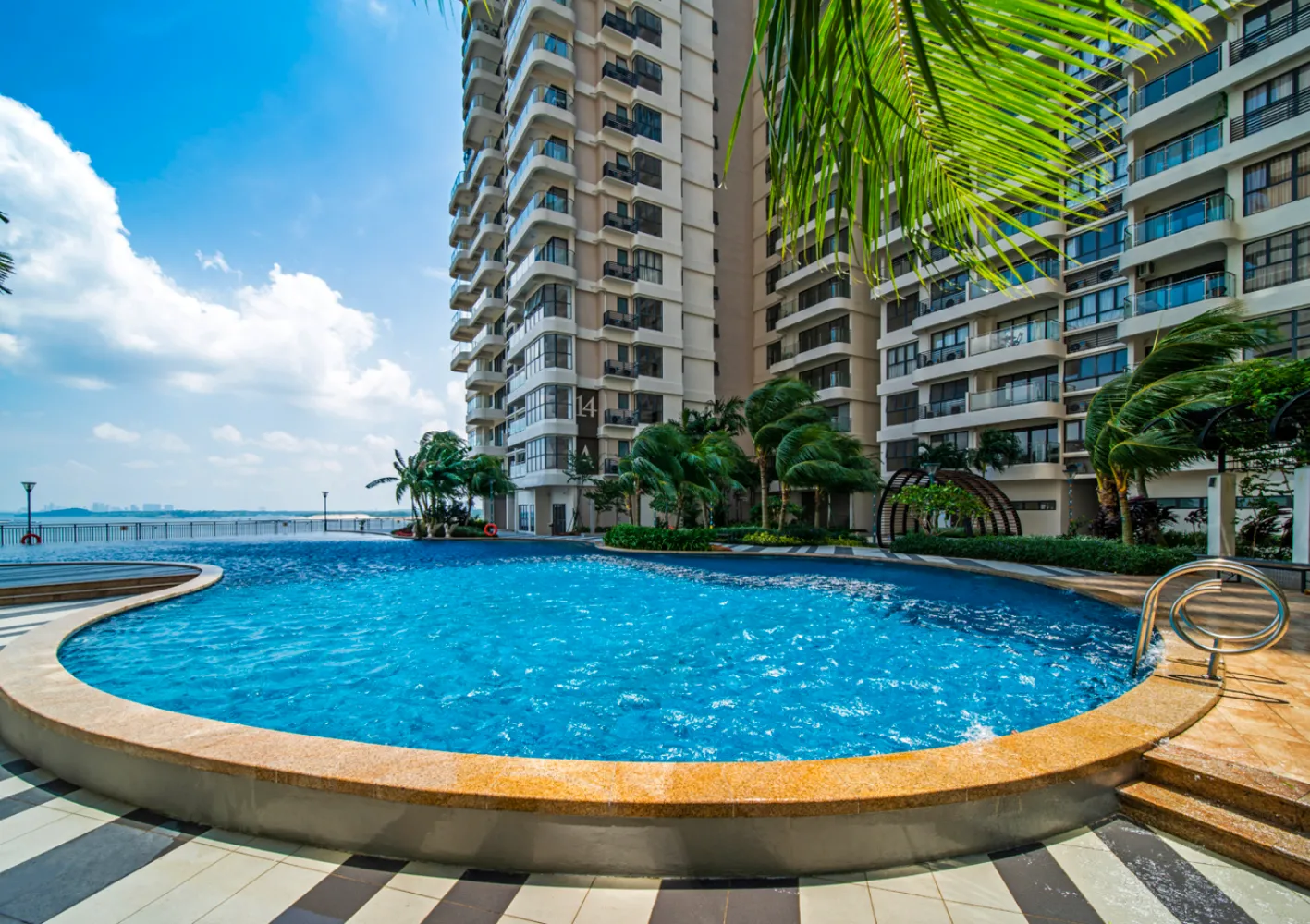 Kolam renang podium gaya resort dikelilingi pokok kelapa dan menara kediaman di Country Garden Danga Bay