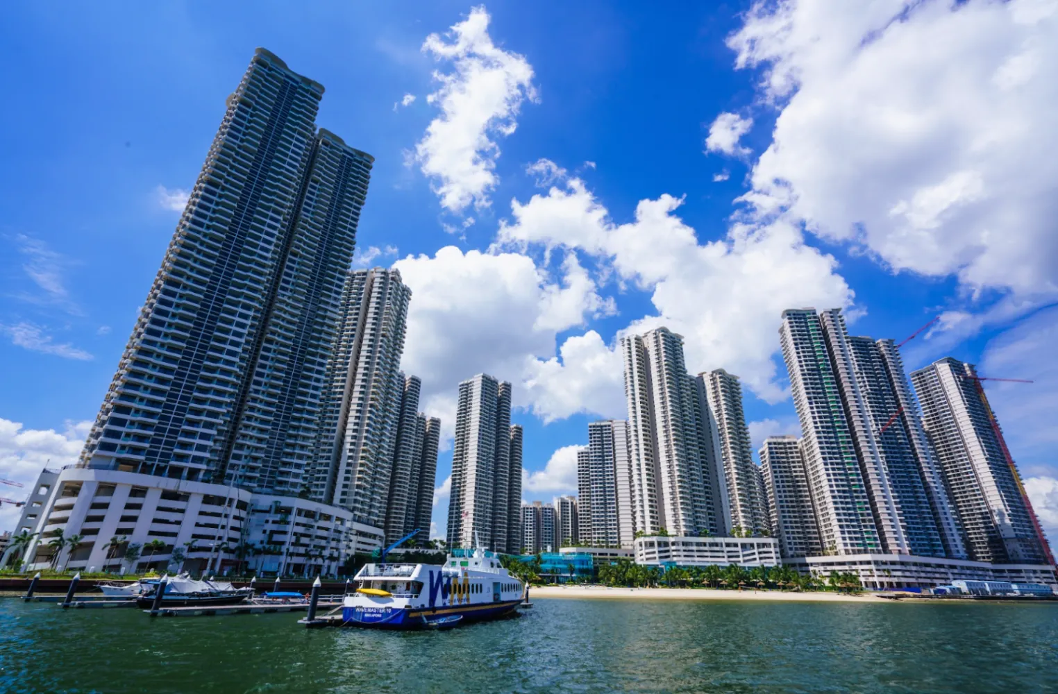 Pemandangan sudut rendah tepi laut menara kediaman Country Garden Danga Bay dan bot di marina