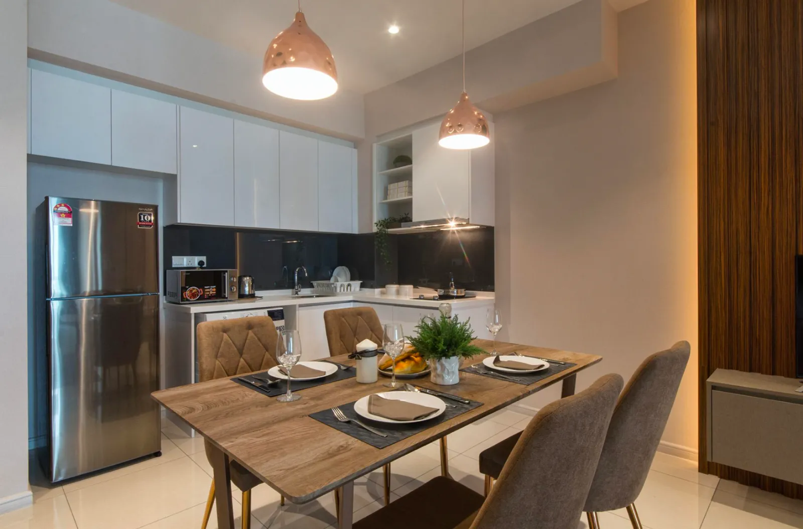 Ruang dapur dan makan berperabot di Elysia Park Residence dengan kabinet putih dan lampu gantung tembaga