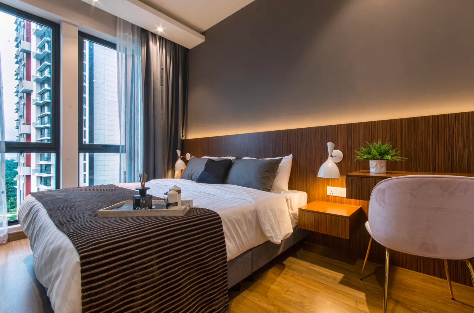 Bilik tidur utama berperabot di unit duplex Elysia Park Residence dengan dinding kepala katil berpanel kayu dan tingkap menghadap bandar