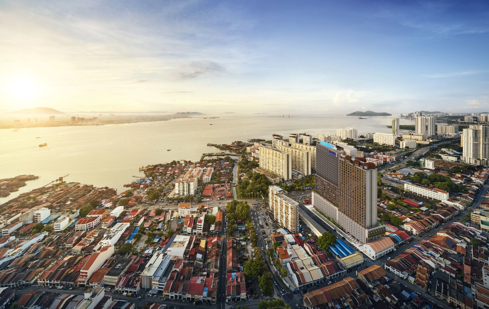 Pandangan udara menara Noordinz Suites yang menjulang di atas rumah kedai warisan UNESCO George Town dengan Selat Pulau Pinang di latar belakang