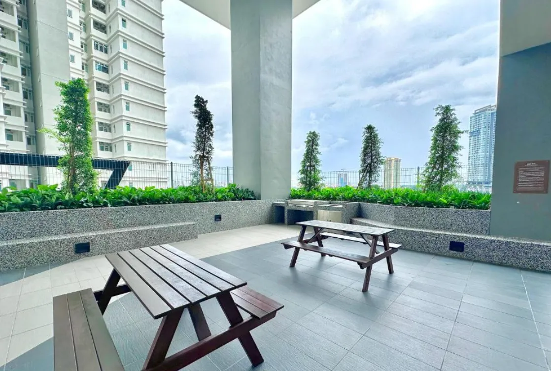 Twin Tower Residence outdoor picnic deck with wooden bench tables and tower view in Bukit Chagar, Johor Bahru, Johor