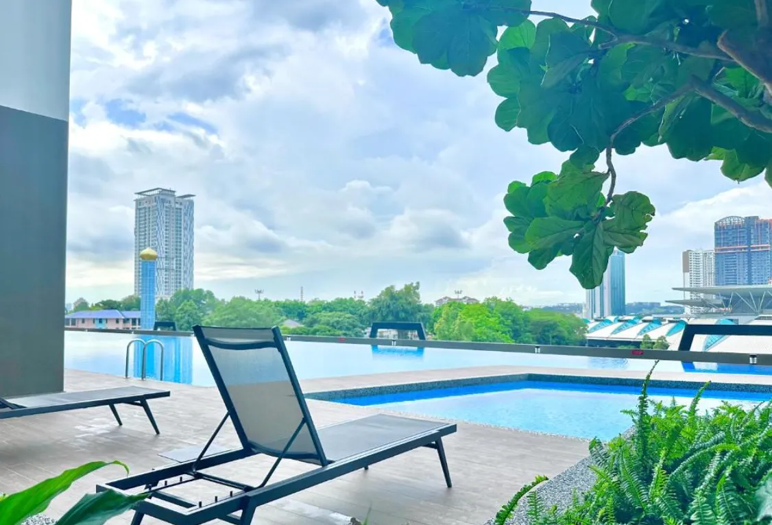 Twin Tower Residence poolside loungers framed by tropical greenery and city view in Bukit Chagar, Johor Bahru, Johor